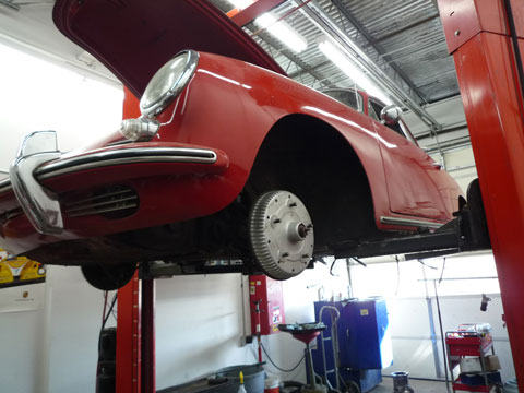 Image of classic red porsche on a car lift.